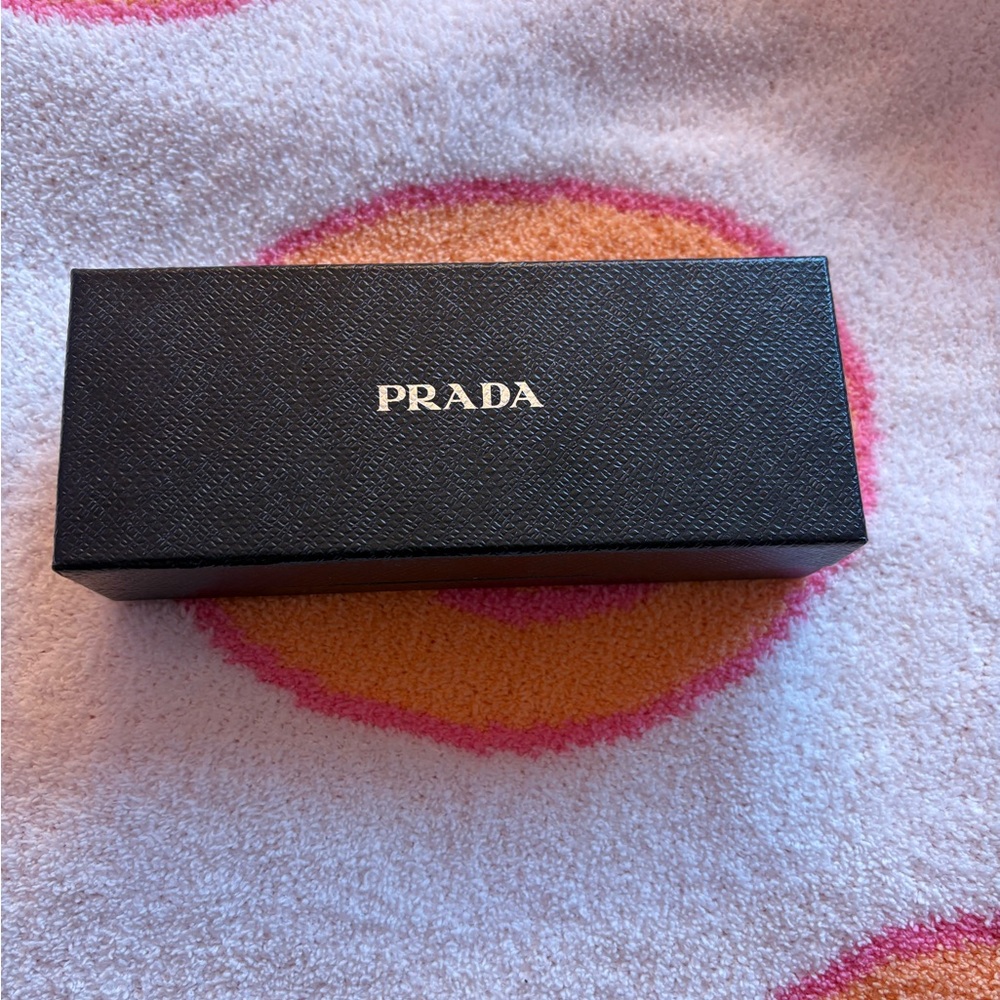 Prada empty box. Black exterior. Silver Prada logo front of box.